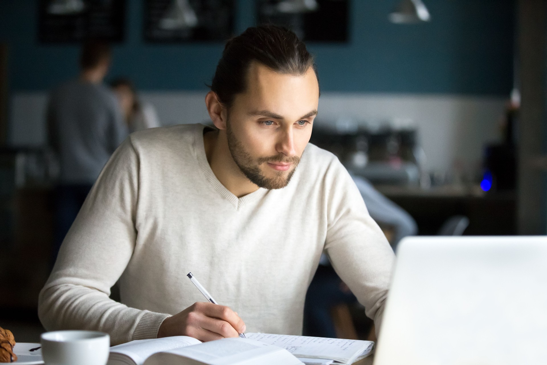 Focused male student studying with laptop out in cafe